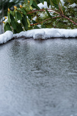 Flat carport roof covered in snow, slush, ice, and water, with clogged downspout drain