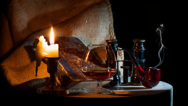 Ein Stillleben mit einer Kerze, Pfeife, Buch, Glas Cognac und einem Opernglas
