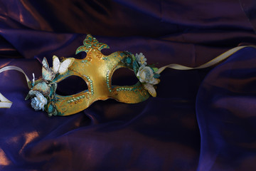 Photo of elegant and delicate gold Venetian mask over purple silk background