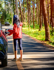 woman driver waiting for helper on car engine breaking out of order in forest of Countryside