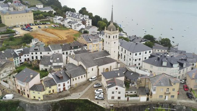 Aerial view of a church in top of a mountain surrounded by old buildings, Eo river with sailing boats in the background, Castropol, Spain, Zoom 