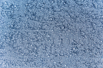 Texture of snow-white snowflakes on the surface. Beautiful frosty snow pattern on the window. Winter Wallpaper with frosty snowflakes on the glass.