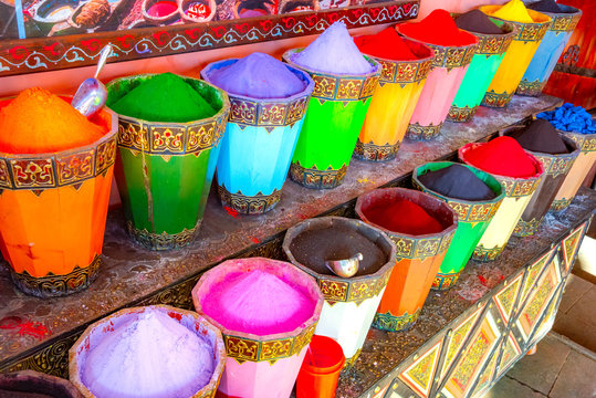 Moroccan powdered dye to color paint for sale in colorful bins with silver scoops in a street vendors store in the old market of Marrakech, Morocco. 