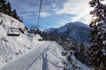 Whistler, British Columbia, Canada. Chairlift going up the mountain during a vibrant and sunny winter day.