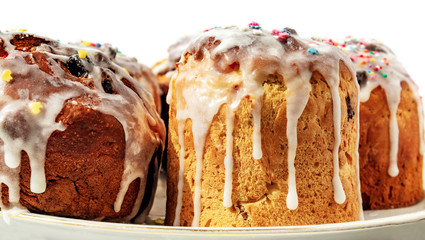 Easter cakes with white flowing icing and colored confetti close-up isolated on a white background. The porous structure of baking closeup. Morning baking