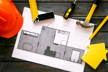 House building plan. Blueprints, instruments, helmet on dark wooden background top-down