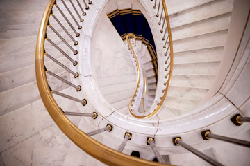 Spiral white marble staircase with gold railing