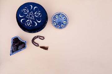 Muslim (islamic) faith concept taqiyah (skullcap), red rosary, dates in the bowl in the Arabic style. White wooden background. layout and Space for text.
