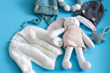 Knitted baby clothes and accessories on a blue background .