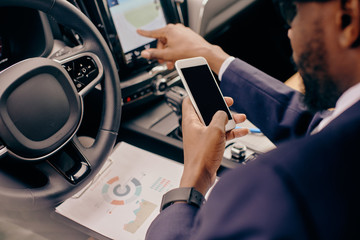 Close up of a man sitting in the car and scrolling through the phone feed.