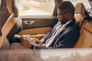 Man on the back seat working on the laptop.
