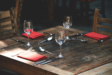 Rustic table served with red napkin, wineglass at an outdoor.