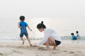 A mother is playing sand and swimming with her son on the beach.