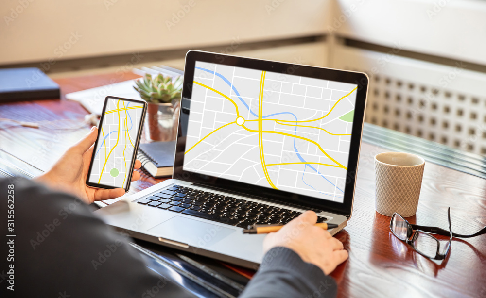 Poster man holding a mobile phone and working with a computer, map on the screens, office business backgrou