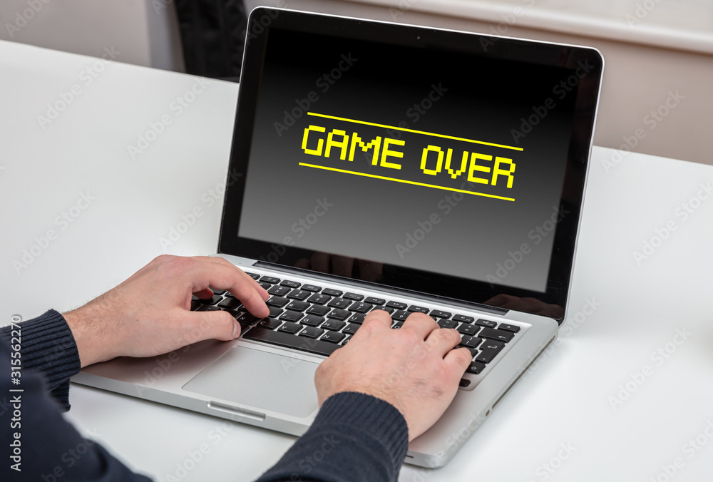 Poster man working with a laptop, game over text message on the screen, office business background.