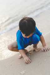 A boy is playing sand and swimming with his brother on the beach.