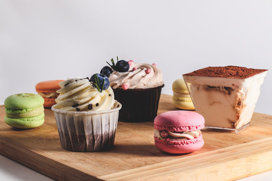 A set of various desserts such as: cupcake, tiramisu, macaron located on the board