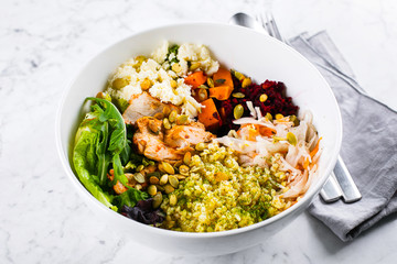 Healthy lunch bowl. Salad with meat, cheese, bulgur and vegetables on marble background. Close-up