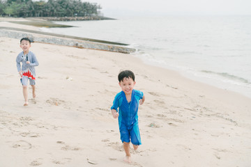 A boy is playing sand and swimming with his brother on the beach.