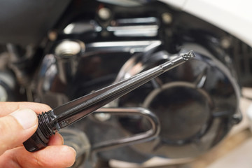 hand of mechanic holding  oil dipstick gauge and check engine oil level on motorcycle in garage .motorcycle maintenance and service and repair concept, selective focus