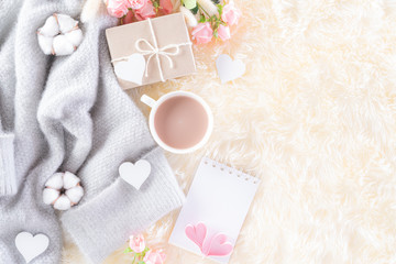 Pink paper hearts with gift box and roses, coffee cup on , beige sweater on cream colour knitted blanket and fluffy background. Love and Valentine's day during Winter concept.