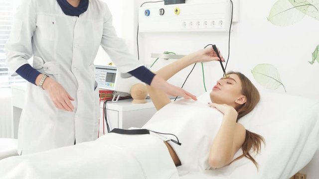 Beauty salon. Young attractive woman in a cosmetic salon lying on the table takes electro therapy.