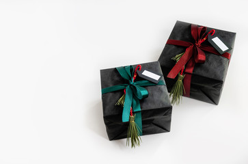 Two gifts are wrapped in black paper and tied with ribbons with a label