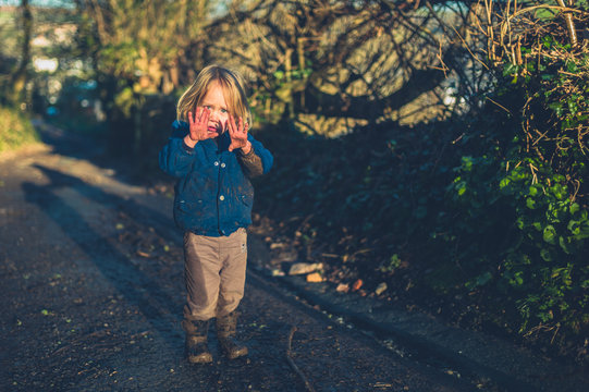 Little toddler on nature walk showing his muddy hands