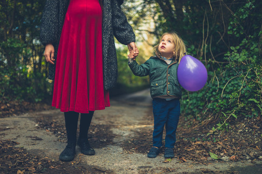 Pregnant Woman With Toddler Holding Balloon In The Woods