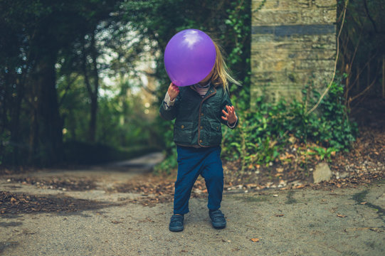 Toddler hiding behind balloon in the woods