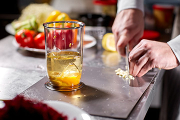 The chef adds garlic. Beating of homemade mayonnaise with olive oil. Mix ingredients for sauce. The chef uses a blender. Step by step sauce preparation