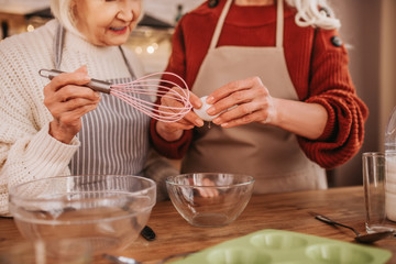 Grey-haired smiling ladies in aprons whipping milk