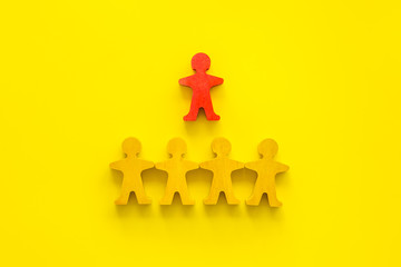 Leadership concept. People cutuots - red figure against others on yellow background top-down copy space