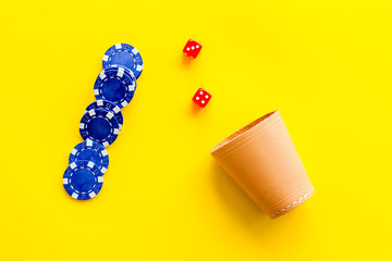 Poker hazard game concept. Chips, dices, cup for dice on yellow background top-down