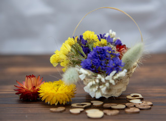 Basket with dried flowers and hearts around on a wooden table top.