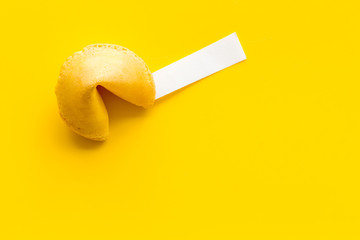 Fortune cookie with prediction inside on yellow background top-down copy space