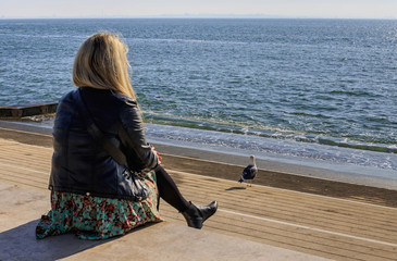 A young woman tourist admires the Atlantic Ocean sitting on the shore