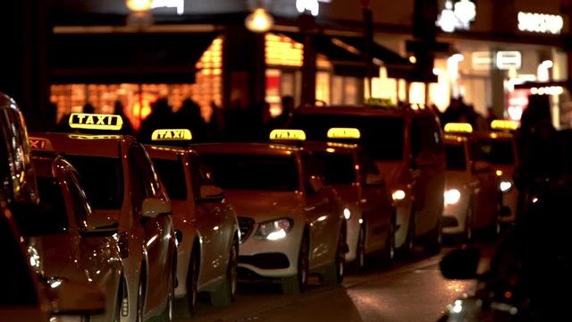 Row of taxi. Night transportation in urban city. Illuminated scene after dark. Downtown munich taxi cars to transport tourist. Slow motion movement