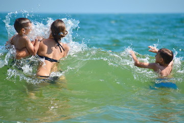Children jumping the waves. Mother with children and a tropical resort.