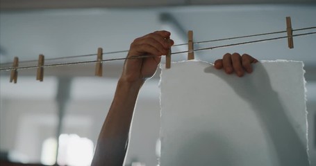 Slow motion of an artisan paper making master is putting to dry high quality handmade paper sheets in a workshop. Shot in 8K. Concept of handmade,high quality,artisan,made in Italy,tradition