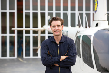 Commercial man pilot in technician suit standing in front of helicopter after check and maintenance engine 