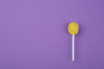 Tasty lemon lollipop on purple background, top view. Space for text