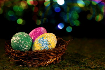 beautiful multicolored Easter eggs in a wicker basket on a shiny background