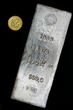 100.97 troy ounce silver bullion bar. One ounce gold round shown for scale.  Precious Metals