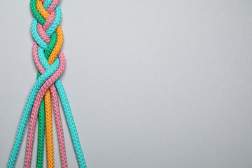 Top view of braided colorful ropes on light grey background, space for text. Unity concept - obrazy, fototapety, plakaty