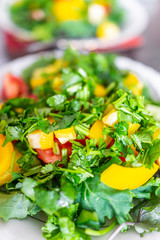 Macro closeup of two fresh salads on plates with baby kale greens, yellow bell peppers and chopped cilantro