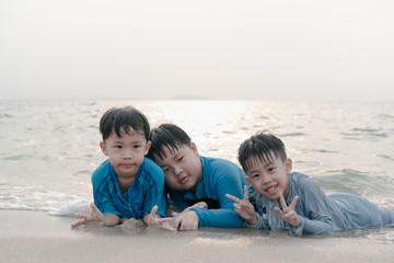 Fototapeta premium A boy is playing sand and swimming with his brothers on the beach.