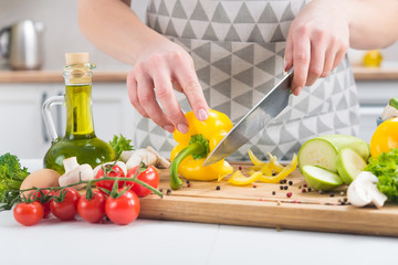 Close up of woman hands cutting vegetables in a kitchen table