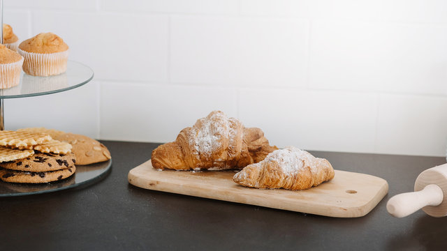 Beautiful fresh pastries. Two croissants covered in white powder on a wooden board. Banner for cusine blog. Copy space