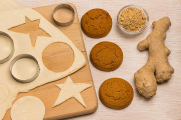 Dough for baking ginger cookies on a cutting board, a form for cutting cookies, cookie blanks like a star and a circle.